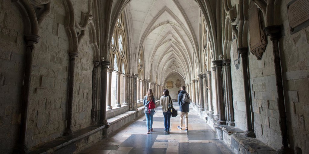 Three tourist visitors exploring the Cloisters of Westminster Abbey